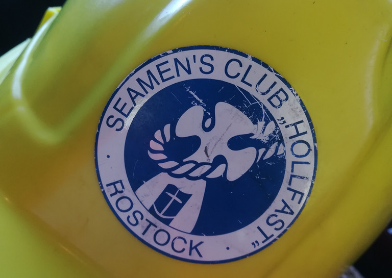 Gelber Schutzhelm mit blauem Logo der Seemannsmission